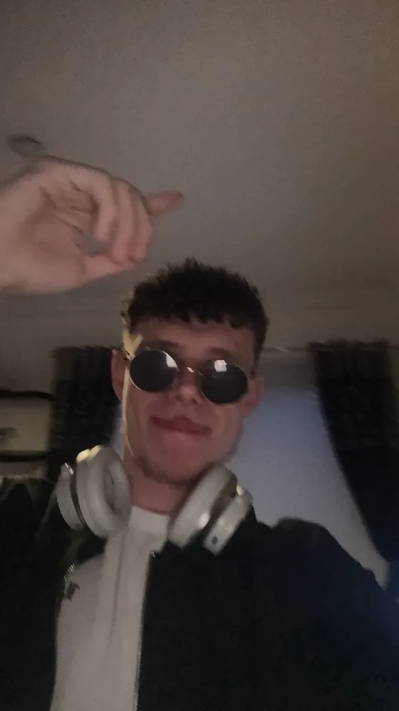 Selfie in round dark sunglasses, headphones round the neck
